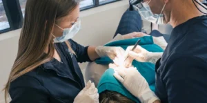 Mohs surgeon wearing a surgical headlight performing Mohs surgery for basal cell carcinoma with an assistant