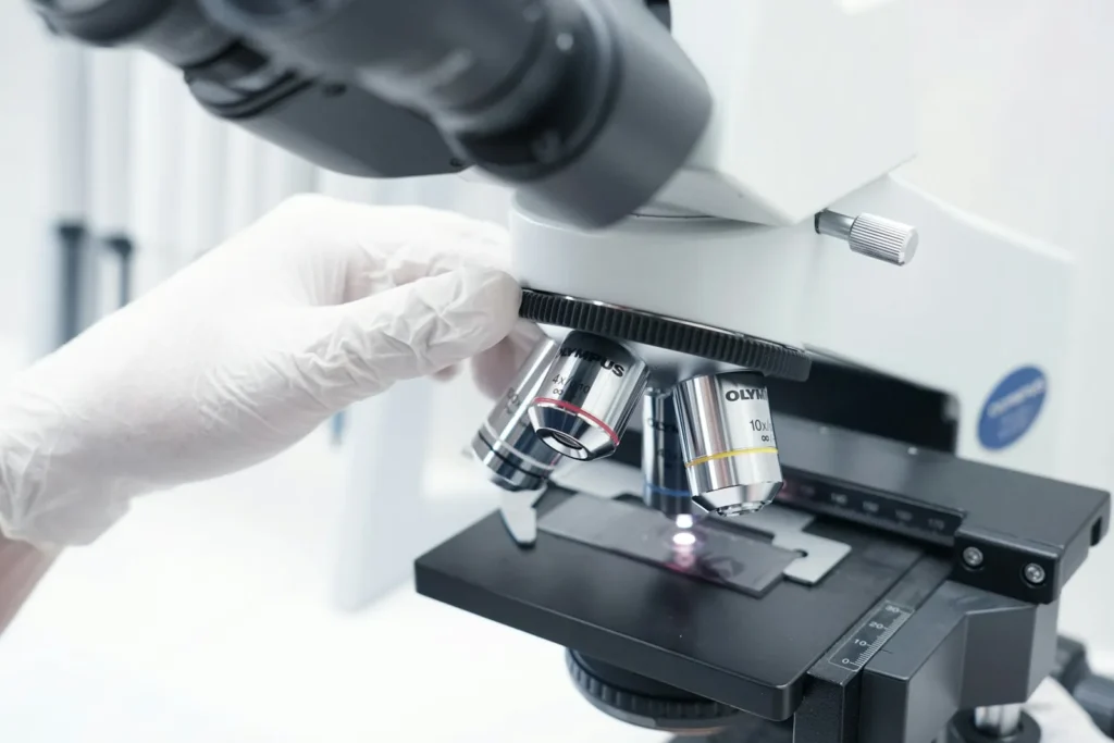 Close-up of a person using a microscope to examine a biopsy slide.